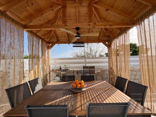 a wooden table with chairs and a bowl of oranges on it at Jomavi Beach Eco-Villa in Polis Chrysochous