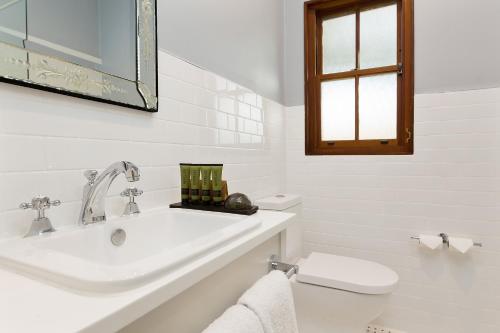 a white bathroom with a sink and a toilet at Peppers Manor House in Sutton Forest