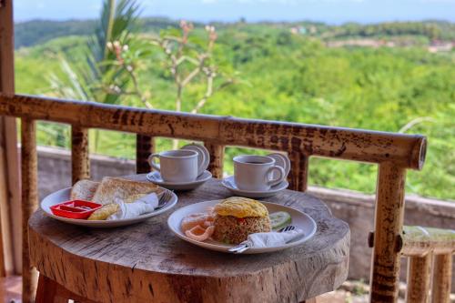 einen Tisch mit zwei Teller Essen und Kaffeetassen in der Unterkunft D Sebuluh Bungalow in Nusa Penida