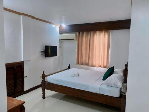 Schlafzimmer mit einem Bett mit weißer Bettwäsche und einem Fenster in der Unterkunft Palawan Rose Inn 2 in Bancaobancao