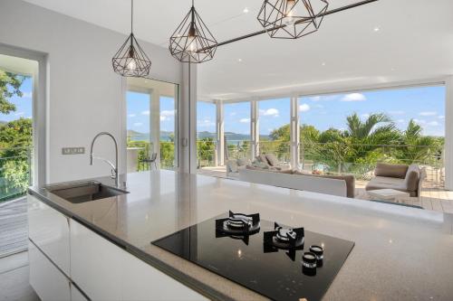 a kitchen with white countertops and glass windows at Villa El Désert in Sainte-Luce