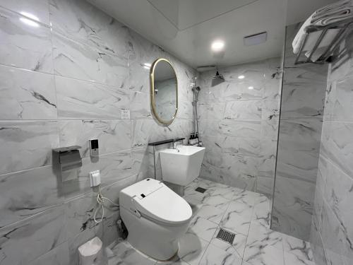 a white bathroom with a toilet and a mirror at Hotel Gate in Incheon