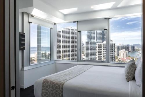 a bedroom with a bed and two large windows at Q1 Resort & Spa - Official in Gold Coast