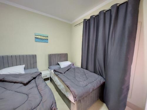 マルサー・アラムにあるLas Cabanas Apartmentのグレーのカーテンが備わる客室のベッド2台