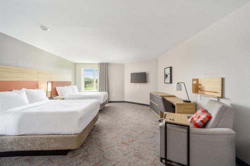a hotel room with two beds and a couch at Candlewood Suites - Ocala I-75 by IHG in Ocala