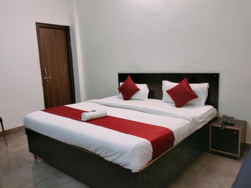 1 dormitorio con 1 cama grande con almohadas rojas y blancas en The Champ Palace, en Lucknow
