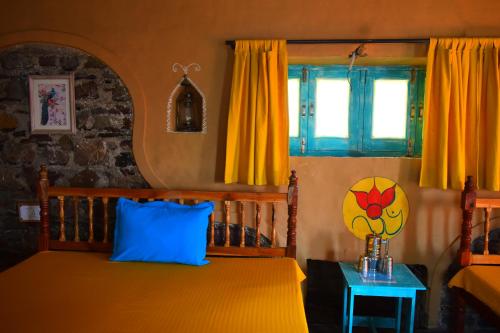 1 dormitorio con cama con almohada azul y ventana en Dirghayu Bhava Retreat, en Dehradun