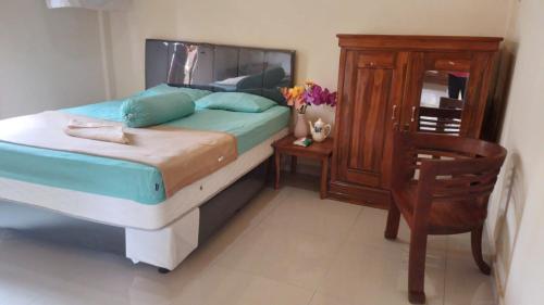 1 dormitorio con 1 cama, armario de madera y silla en Anish Homestay, en Jatiluwih