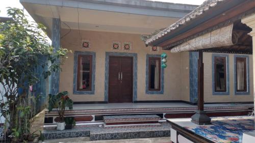 une maison avec une porte en bois dans une cour dans l'établissement Anish Homestay, à Jatiluwih
