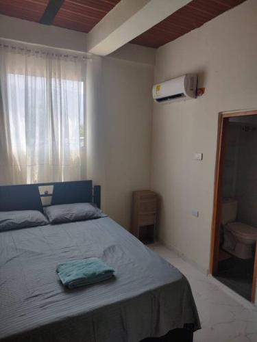 a bedroom with a bed and a window with a toilet at Apartamento Dorado Sunset in Santa Marta