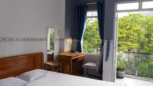 a bedroom with a bed and a desk and a window at Sunny Homestay Quy Nhơn in Quy Nhon