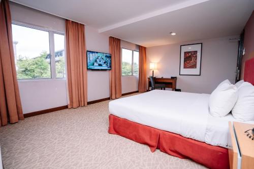 a hotel room with a large bed and windows at Jewels Hotel in Kota Bharu