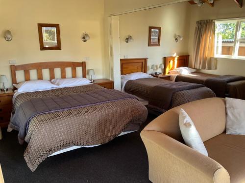 a hotel room with two beds and a couch at Alpine Springs Motel in Hanmer Springs
