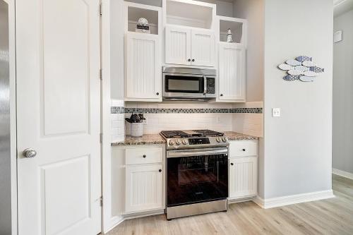 a kitchen with white cabinets and a stove and microwave at Casa de Flip Flops in Rockport