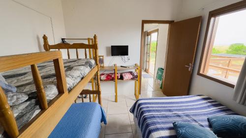 een slaapkamer met 2 stapelbedden en een televisie bij Bella Praia apartamento Golfinho in Passo de Torres