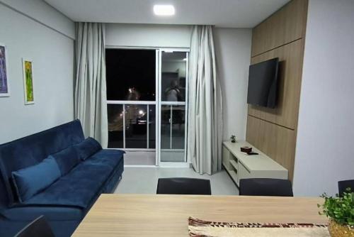 un salon avec un canapé bleu et une table dans l'établissement M6 - Apto, Cancun, Novo e confortável, à Foz do Iguaçu