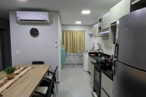une cuisine avec une table en bois et un réfrigérateur dans l'établissement M6 - Apto, Cancun, Novo e confortável, à Foz do Iguaçu