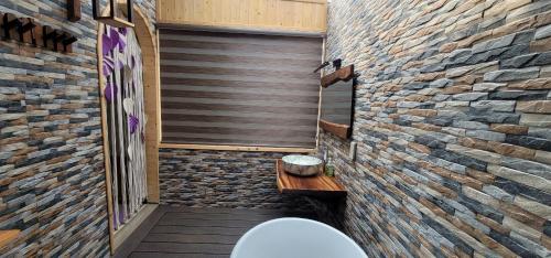 a bathroom with a toilet and a brick wall at La Fleur Glamping in Minrong Sekang