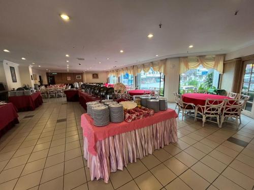 uma grande sala com mesas e cadeiras com mesas vermelhas em Hotel Rosa Passadena em Cameron Highlands