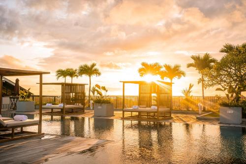 a resort with a swimming pool and palm trees at Cross Paasha Bali Seminyak in Seminyak