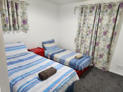 2 camas individuales en una habitación con cortinas en An inner city 4-bedroom house with two carparks en Wellington