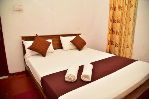 a bedroom with a bed with two pillows at Rusara Villa in Tissamaharama