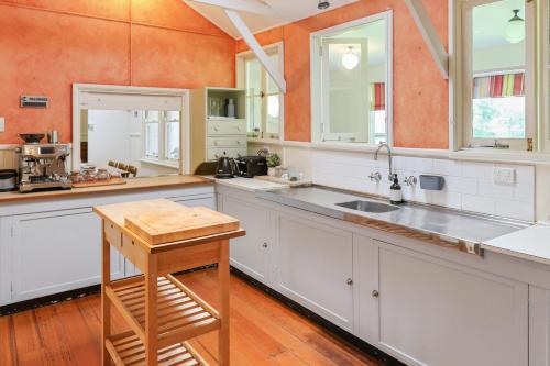 uma grande cozinha com armários brancos e uma mesa de madeira em Pink Cabin By Host on the Coast em Barwon Heads