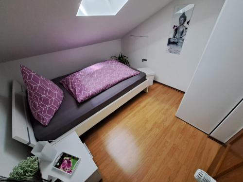 a small room with a bed with purple pillows at Wohlfühlapartment Erlenberg in Thurmansbang