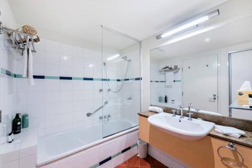 uma casa de banho com uma banheira, um lavatório e um chuveiro em 'Harbour Highlight' Poolside Living on Esplanade em Darwin