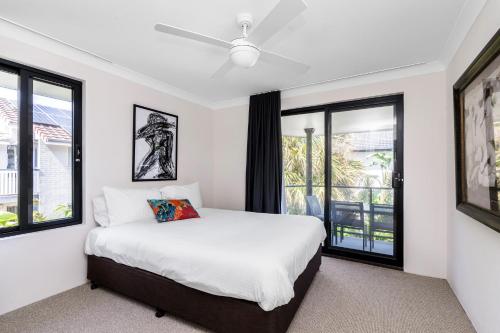 1 dormitorio con cama blanca y ventanas en Byron Bay Accom Unit 3 5-9 Somerset Street - Summer Central, en Byron Bay
