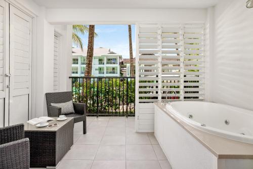 a white bathroom with a tub and a chair at Peppers Beach Club in Port Douglas