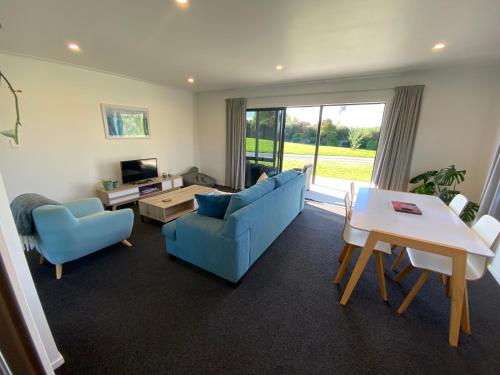 a living room with a blue couch and a table at Soul Sanctuary, with outdoor bath in Raglan