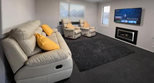 a living room with a couch and two chairs and a tv at MataMata in Matamata