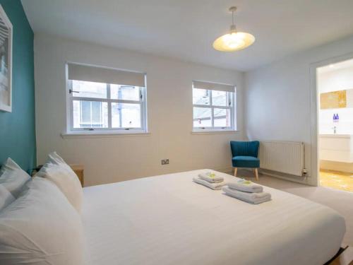 - une chambre avec un grand lit blanc et une chaise bleue dans l'établissement Pass the Keys Stylish West End Detached Mews, à Glasgow