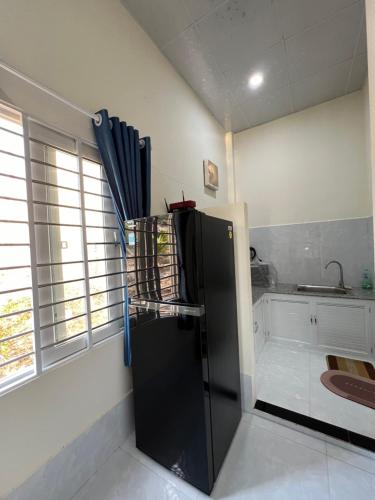 a kitchen with a black refrigerator in the corner at House Mũi Né Phan Thiết KentTown in Ấp Thiện Sơn