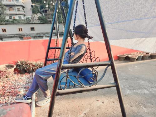 a young woman sitting on a swing at Riverbank Guest House With Restaurant & self cooking facility in Guwahati
