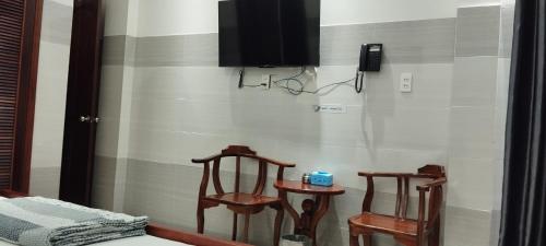 een kamer met 2 stoelen en een tv aan de muur bij An An Hotel in Ho Chi Minh-stad