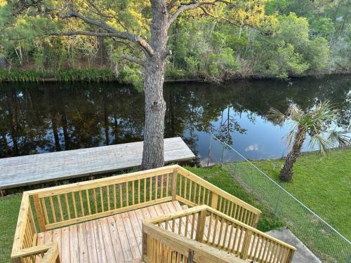 a wooden bench next to a tree next to a river at Bay Breeze Bliss-Hot Tub, Bar and Canal 5mi to Beach in Shoreline Park