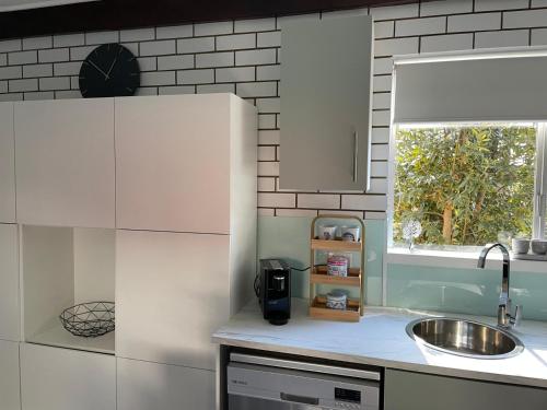 eine Küche mit einem Waschbecken und einer Uhr an der Wand in der Unterkunft Modern studio with private patio in Dernancourt