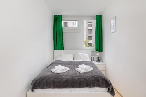 a bedroom with a bed with green curtains at Ecru Apartment near Norblin Factory WWA76 in Warsaw