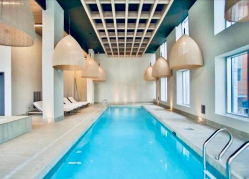 a large swimming pool with blue water in a building at Spectacular Skyline Views - Downtown Montreal - Luxury Condo & Penthouse in Montréal