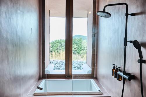 a bathroom with a glass shower with a window at Snow Peak YAKEI SUITE ABURAYAMA FUKUOKA in Fukuoka