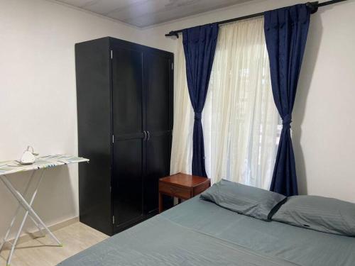 1 dormitorio con 1 cama, armario negro y ventana en Cómoda casa cerca al centro, en San José del Guaviare