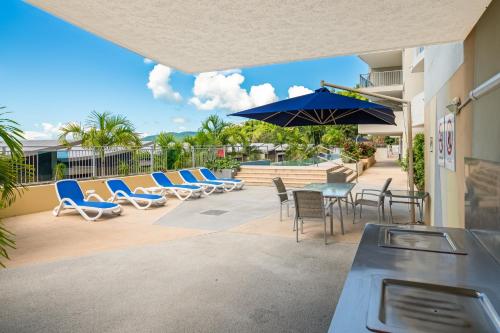 a patio with chairs and a table and umbrella at Azure Sea Whitsunday Resort in Airlie Beach