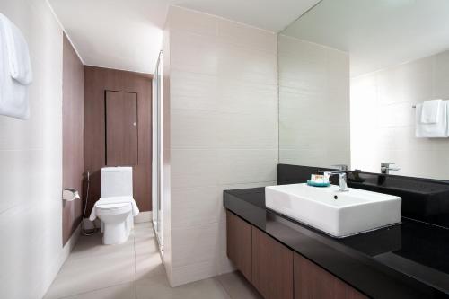 a bathroom with a white sink and a toilet at Lily Hotel Bangkok in Bangkok