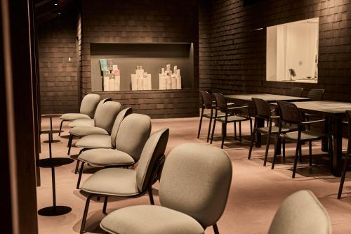 a waiting room with chairs and tables and a screen at Snow Peak YAKEI SUITE ABURAYAMA FUKUOKA in Fukuoka