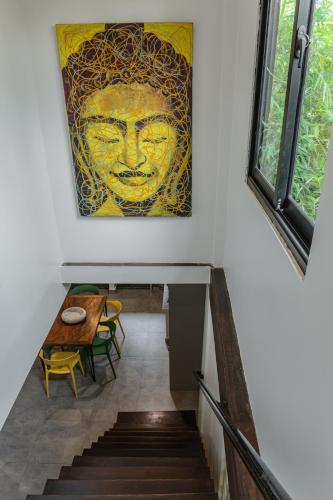 a staircase with a painting of a face on the wall at Mes trois coeurs in Phumĭ Réach Born