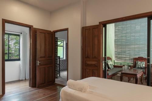 a bedroom with a bed and a sliding glass door at Mes trois coeurs in Phumĭ Réach Born