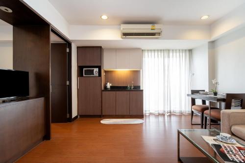 a living room with a couch and a table and a kitchen at Lily Hotel Bangkok in Bangkok