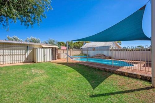 a backyard with a swimming pool with a blue canopy at Home in Lamington in Kalgoorlie